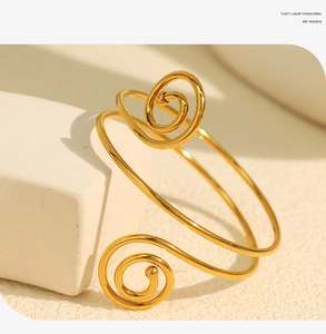 Close-up of golden double spiral open bangle featuring a luxury mirror polished finish