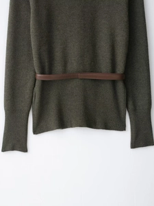 Détail d'un pull en maille olive foncé avec motif à losanges et ceinture en cuir marron