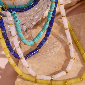 Detail of colorful beaded necklaces with natural stones and golden spacers on stone surface