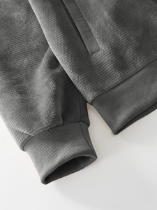 Detail of dark grey hoodie showing honeycomb waffle texture and ribbed cuff design