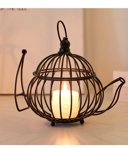 Detail showing a black metal wire teapot candle holder on white marble tabletop