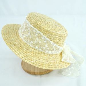 Detail of elegant lace ribbon bow on texture straw sun hat for summer seaside vacation