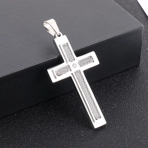 Détail macro d'un pendentif croix en maille argentée à deux couches avec cristal sur boîte noire
