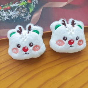 Close-up of two white plush reindeer doll pins with red noses on a rustic wooden background