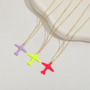 Detailed view of three glossy airplane pendants in purple, yellow, and red on gold chains