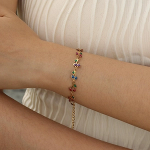 Detail of a gold bracelet featuring multi-colored glitter cherry charms on a thin metal chain