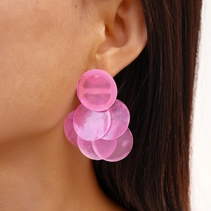Close-up of pink round layered faux shell earrings worn by a model in profile
