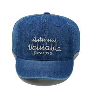 Detail view of vintage blue denim texture and white embroidery on a short brim cap