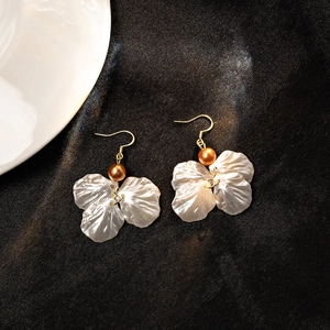 Elegant white petal drop earrings with gold hooks and bronze beads on dark fabric