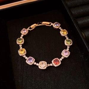 Macro detail of 18k gold plated bracelet featuring colorful square zircons on black velvet