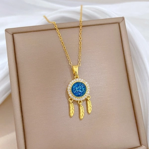 Macro view of golden dreamcatcher necklace with blue center and feather charms