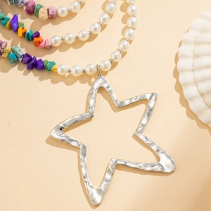 Detail of multi-layer necklace with colorful beads, pearls and hammered star pendant