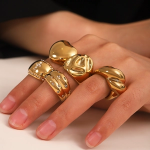 Close-up of golden ring set featuring croissant and heart designs on model hands