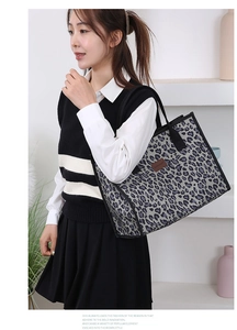 Detail of grey leopard print canvas tote bag with black handles and branded label