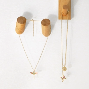 Detail of gold hummingbird and dragonfly pendants with colorful zircon stones on display