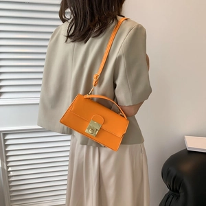 Chic orange leather crossbody bag with gold buckle shown from a stylish back view