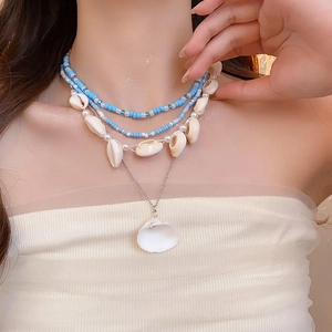 Detail of bohemian layered necklace set featuring sea shells, beads, and pearls
