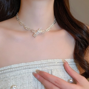 Detail der silbernen Schleife mit Perle am Hals des Models für eleganten Stil