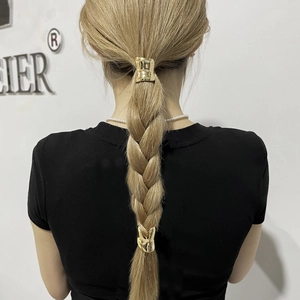 Detail of minimalist gold metal ponytail clips with glossy finish on blonde braided hair