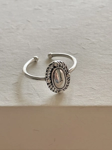 Detailed shot of silver oval ring with vintage braided texture on beige background