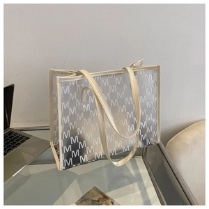 Detail view of large capacity transparent PVC tote bag with M-letter print on office desk