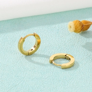 Classic gold stainless steel hoop earrings on a minimalist blue textured background