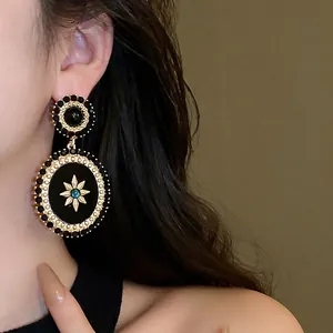 Vintage style black oval earrings with gold star and turquoise stone on model