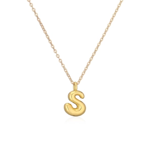 Macro view of polished gold plated letter S pendant and fine chain necklace detail