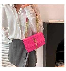 Detail of fuchsia quilted crossbody bag with gold SS logo, metal tassel and chain strap