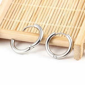 Polished silver stainless steel hoop earrings with hinged closure on bamboo background