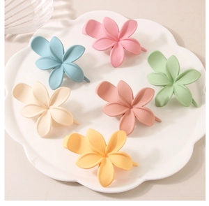 Détail de six pinces à cheveux fleur mate en couleurs pastel sur plateau céramique