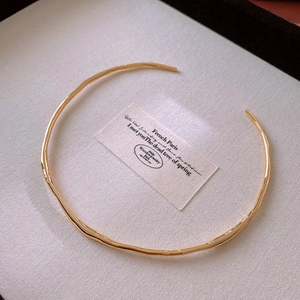 Detailed top view of a wavy gold plated minimalist choker necklace on jewelry box lining