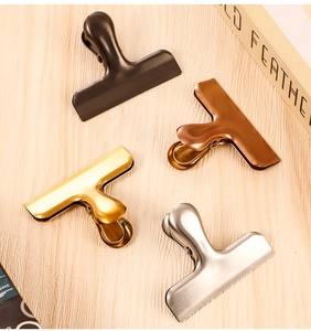 Detail of four multi-purpose stainless steel clips in black, bronze, gold and silver finishes