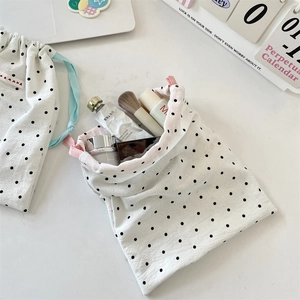 Close-up of polka dot drawstring storage bags with cosmetics on a white desk