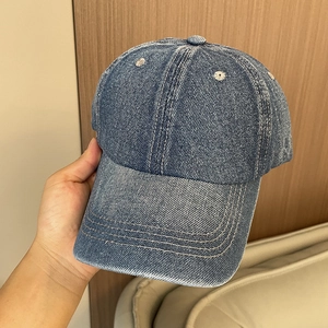 Close-up of vintage washed denim baseball cap with detailed stitching and blue texture