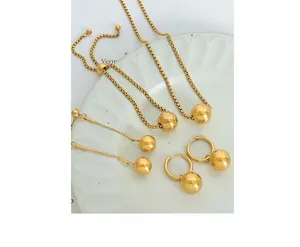 Detailed view of gold plated steel ball pendant jewelry set on a ceramic plate