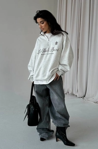 Detail of grey half-zip sweatshirt featuring artistic chest letter print and relaxed fit