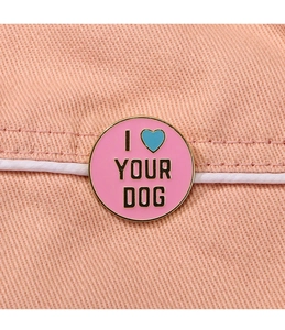 Detail of pink enamel badge with 'I Love Your Dog' text on orange denim fabric