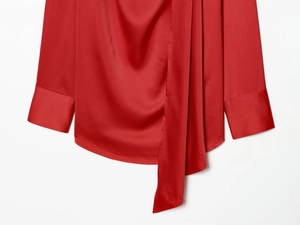 Detailed view of red satin blouse featuring a pussy-bow neckline and elegant long sleeve cuffs