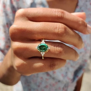 French retro gold ring with green gemstone and clear side stones on a model finger