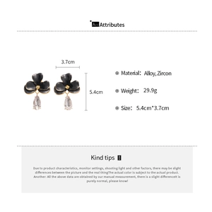 Détail de boucles d'oreilles fleurs avec pétales noirs, cristaux et pendentifs zircon