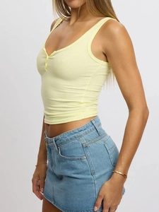 Detail view of a pale yellow ribbed knit crop top with stylish button neckline design