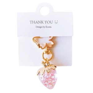 Pink transparent strawberry keychain with gold leaves and glitter on white card