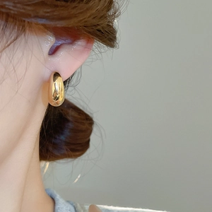 Primo piano di eleganti orecchini a goccia d'oro sull'orecchio di una modella con finitura