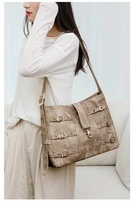 Detail of vintage brown PU leather crossbody bag with multiple metal buckles and straps