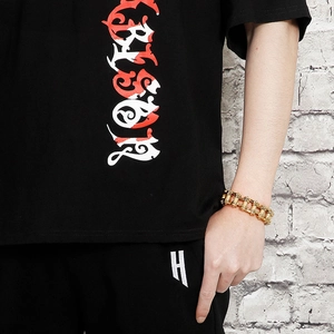 Close-up of golden bicycle chain style bracelet worn by a model in streetwear fashion