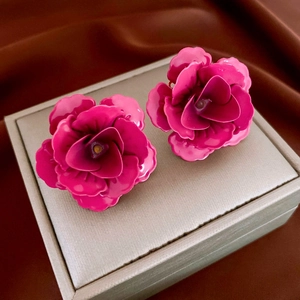 Gros plan sur des boucles d'oreilles roses 3D avec pétales brillants sur écrin beige