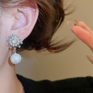 Close-up of snowflake pearl earrings with silver needle and sparkling zircon accents