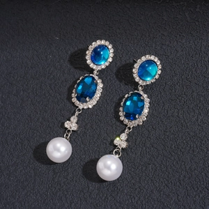 Detailed macro view of vintage earrings with blue gemstones, rhinestones and white pearls