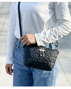 Women's black crossbody bag with heart quilting and golden swan tassel detail